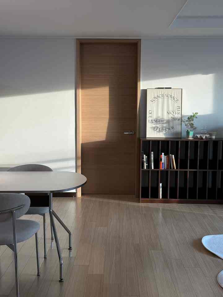 ナチュラルな木目調が際立つリビングとキッチンの空間、スチール脚のダイニングテーブルとファブリックチェアが配置されたモダンなインテリア