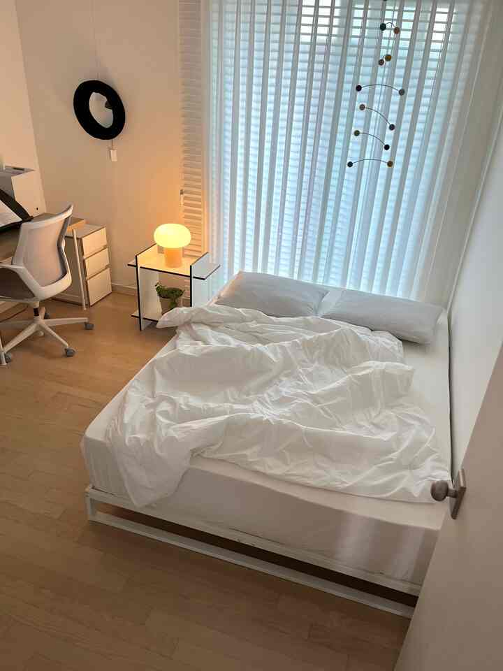 ホワイトとナチュラルカラーが調和した子供部屋、ミニマルな鉄製ベッドフレームと机が配置された雰囲気のある寝室