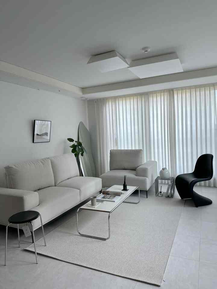 White-toned living room featuring a minimalist sofa and coffee table with a calm atmosphere