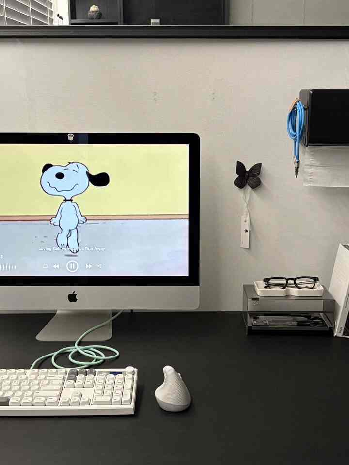 モノトーンのホームオフィス、黒いデスクに白いキーボードと緑色の高速充電ケーブルが配置された清潔感のある空間