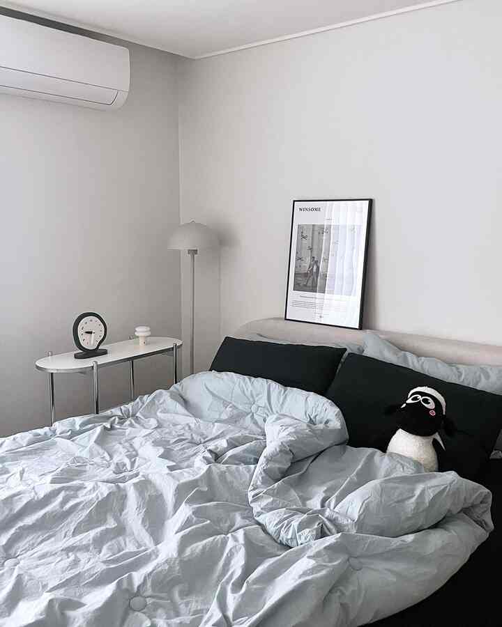 White and sky blue toned bedroom featuring black accent cushions and a minimal nightstand for a cozy atmosphere