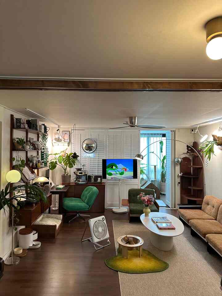 温かみのあるブラウンとグリーンの色調のリビング、ヴィンテージソファと白いコーヒーテーブルが配置された落ち着いた印象的な空間