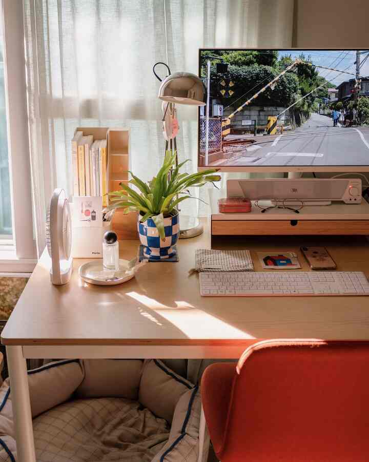 白と木目調の調和したホームオフィス、デスク上のチェッカーボードのセラミック鉢と赤い椅子が印象的な暖かい雰囲気のインテリア