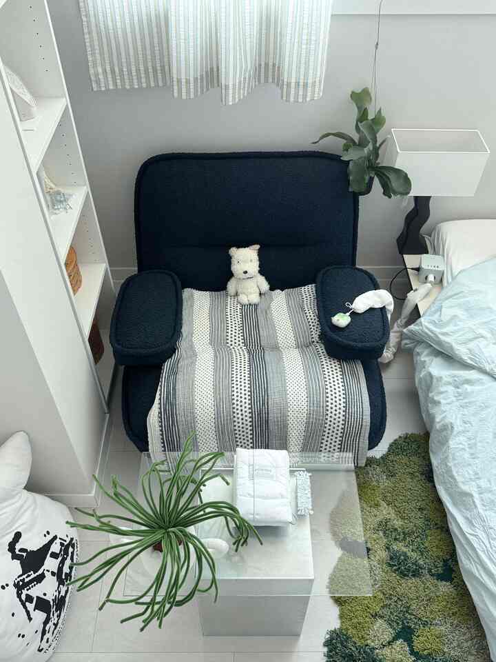 ネイビーカラーのアームチェアとナチュラルな色調のコンパクトなリビング、植物とラグが温かみのある雰囲気を演出するインテリア