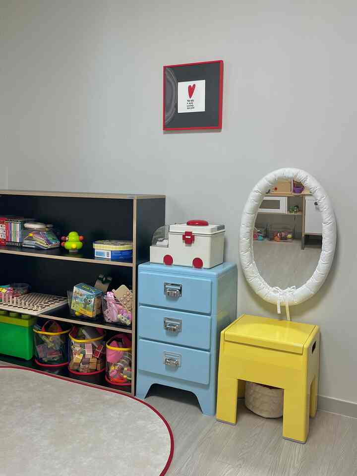 ベージュ調の壁と床、子供のおもちゃと収納家具が配置された明るい子供部屋の空間