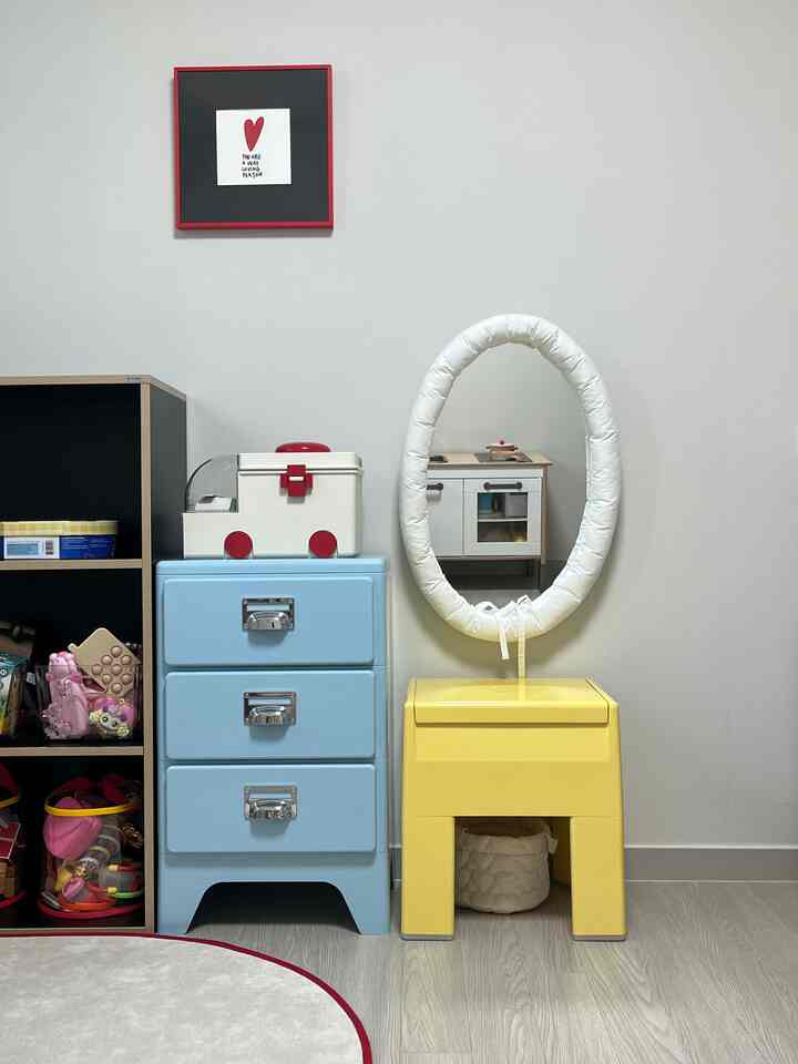 白い壁と青い引き出し、黄色いスツールが配置された赤ちゃんの遊び部屋の雰囲気のあるインテリア
