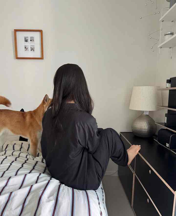 白と黒のトーンの寝室、ベッドとナイトテーブル、犬と人がいる落ち着いた雰囲気のインテリア