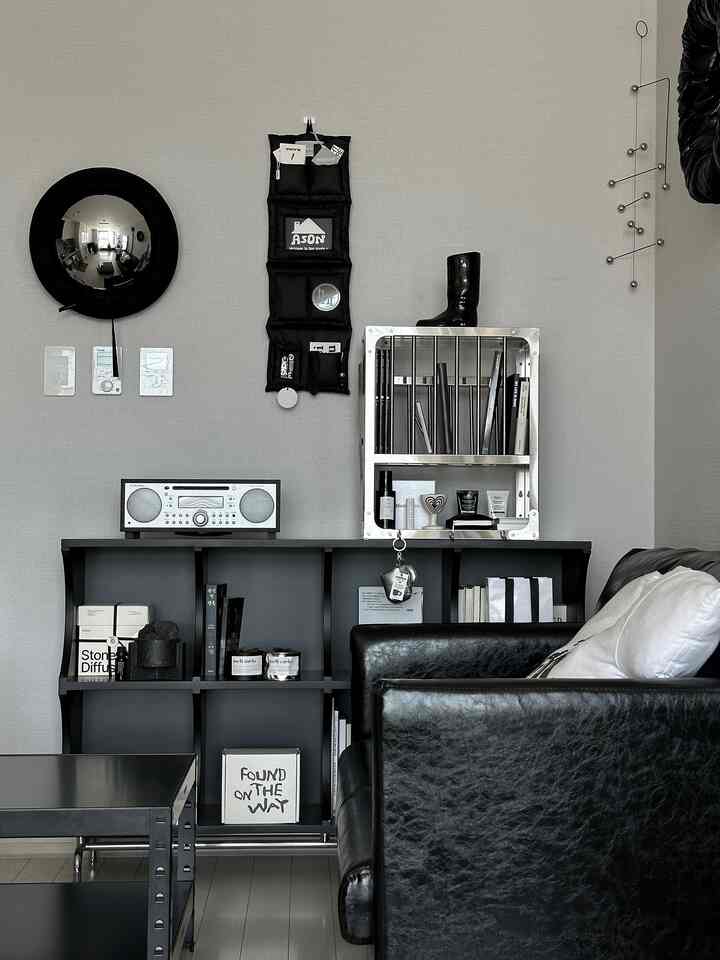 グレーの壁と黒いレザーソファ、メタルの棚、モビールが配置されたシンプルでモダンなリビング