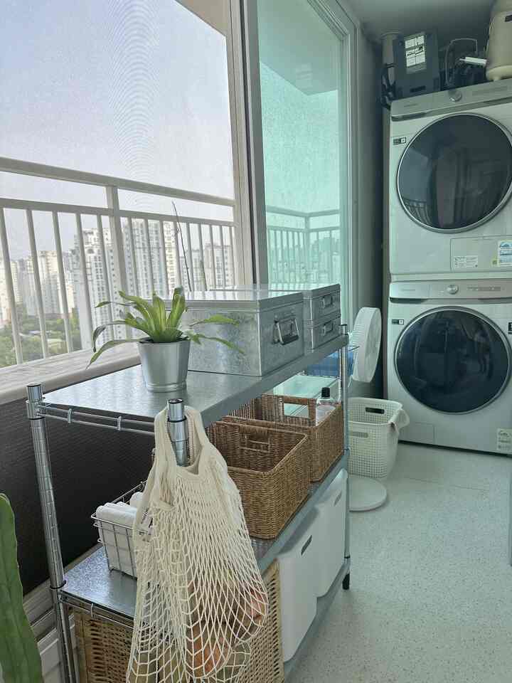 白とグレーの色調のベランダ、ステンレス棚と洗濯機が整然と配置された実用的な収納空間