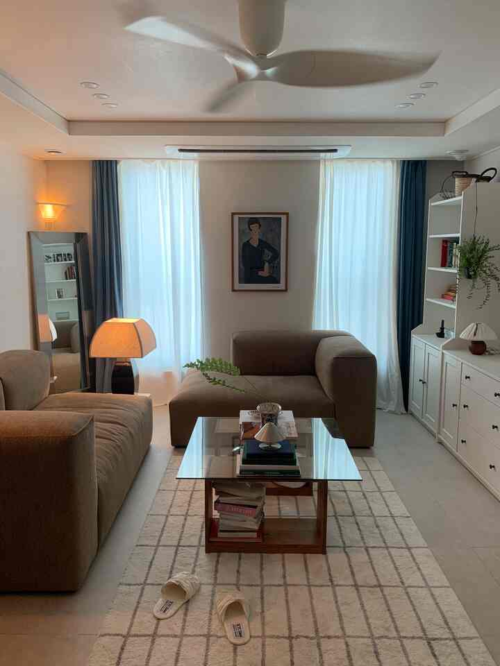 ホワイトとブラウンの色調のリビング、ソファとラグが配置された落ち着いた雰囲気のインテリア