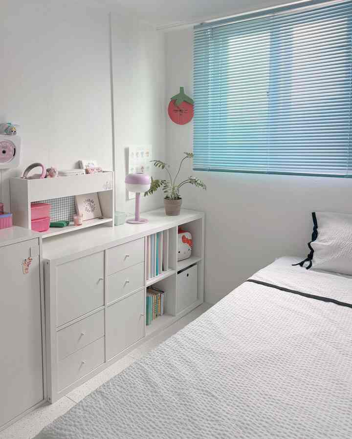 Bright white bedroom with blue blinds featuring storage units and child-friendly decor in a neat and compact space
