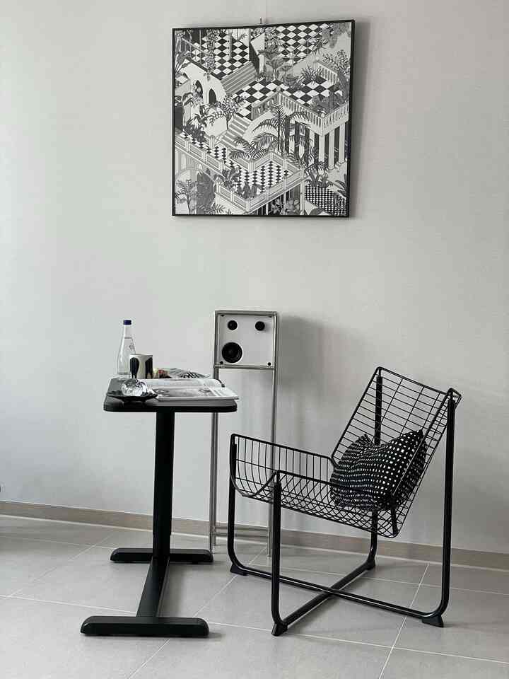 Monotone black and white bedroom featuring a metal side table and wire chair with a minimalistic style