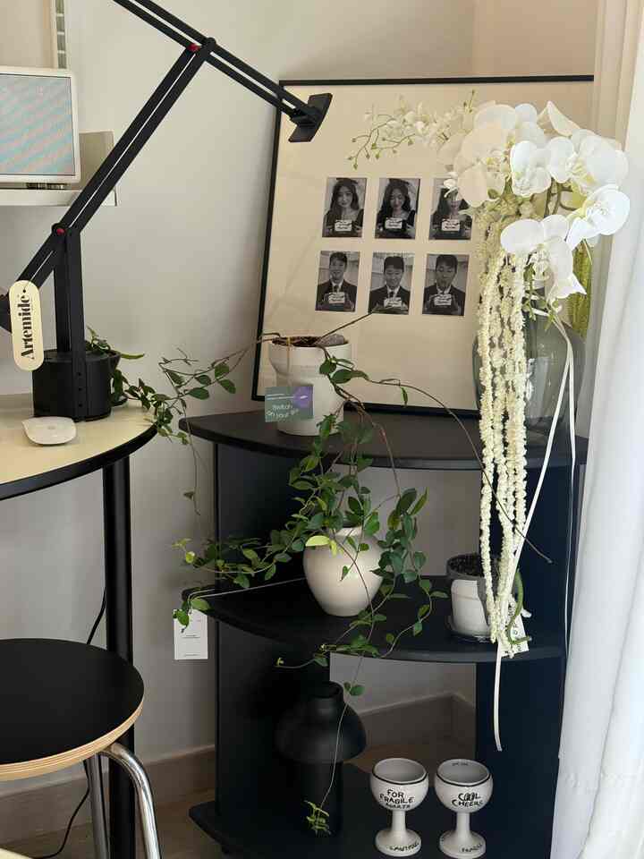 白と黒を基調としたモダンな空間、コーナーシェルフや植物、テーブルランプが配置されたすっきりしたインテリア