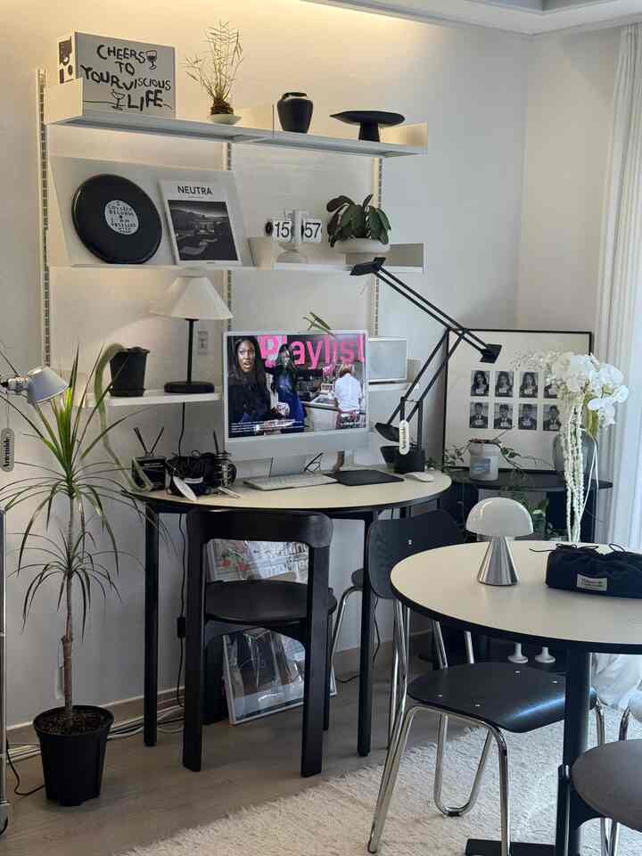 White and black toned home office space featuring a desk, round dining table, and modern lamps in a clean interior