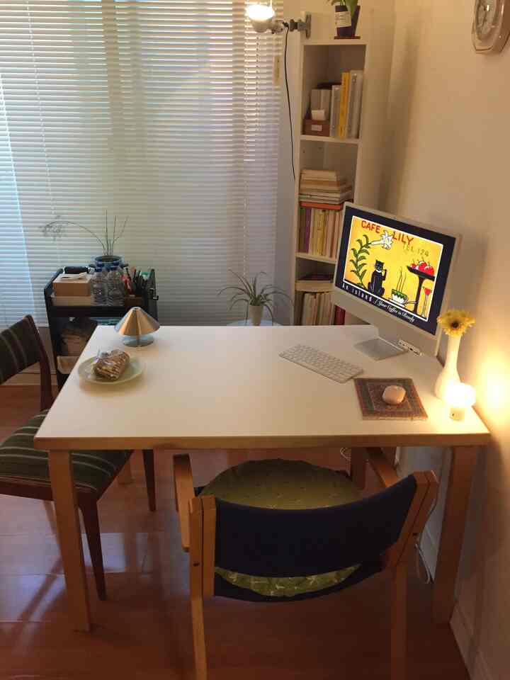 白と茶色のトーンでまとめられたコンパクトなホームオフィス、机と本棚が配置された整った作業空間