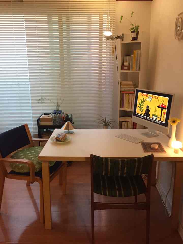 白と木目調の2人用ホームオフィス、ブラインドと本棚が配置された印象的でモダンなインテリア