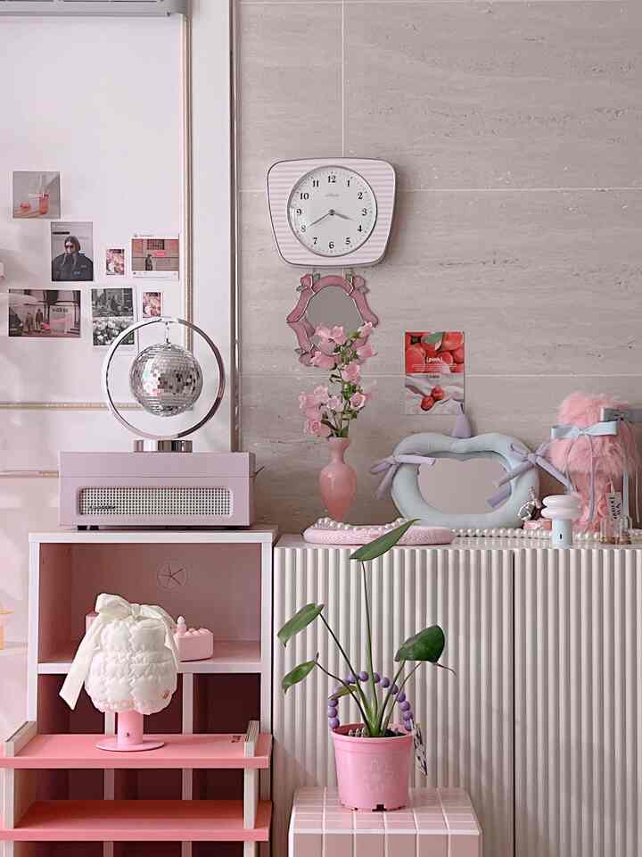Pink-toned living room wall featuring a pink vase, clock, and various decorative objects arranged neatly for a charming atmosphere