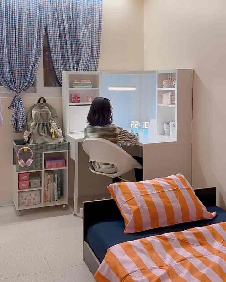 A cozy and practical kids' room in white and orange tones, featuring a corner desk and bed