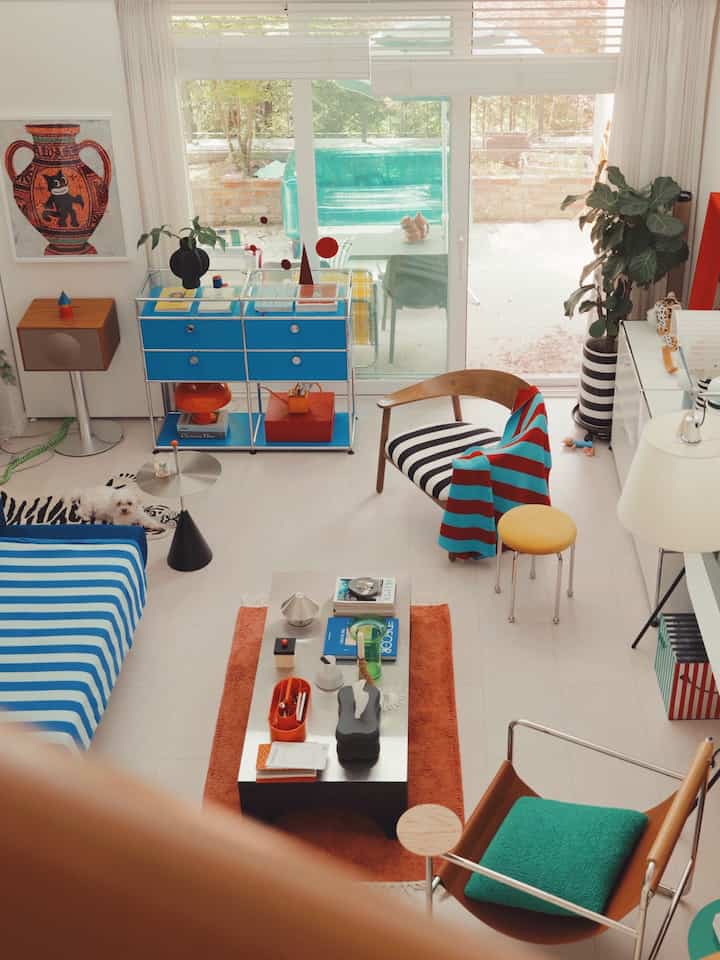 明るい白を基調とした青い家具のモダンなリビング、ペットの犬と植物が配置された雰囲気のある空間