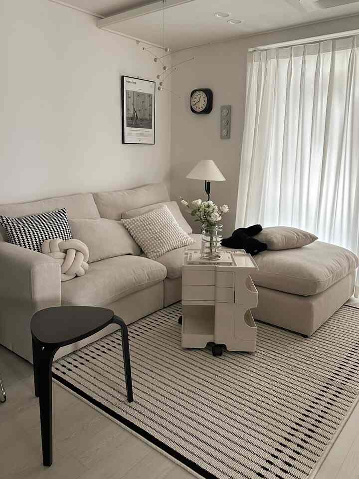 ホワイトとベージュのトーンのリビング、モダンなソファとトロリーが配置された落ち着いた印象の空間