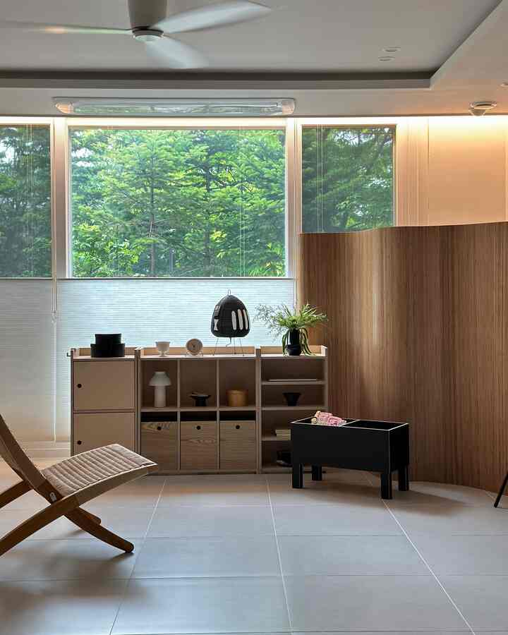 Natural wood tone living room featuring a simple armchair, bookshelf, and curved room divider with a calm atmosphere