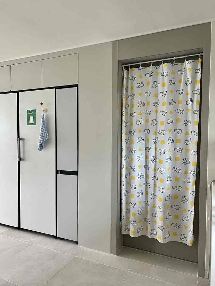 A clean, modern kitchen gap storage area featuring white cabinetry and a yellow-accented curtain