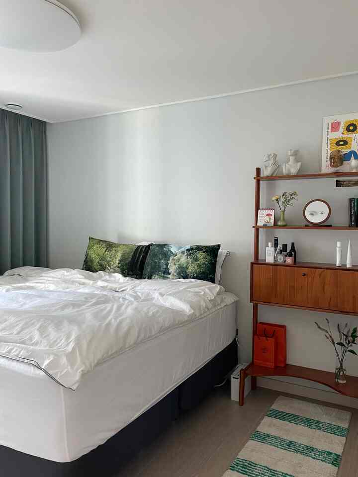 White and navy toned bedroom featuring a large bed and wood tone shelving cabinet with a clean, cozy atmosphere