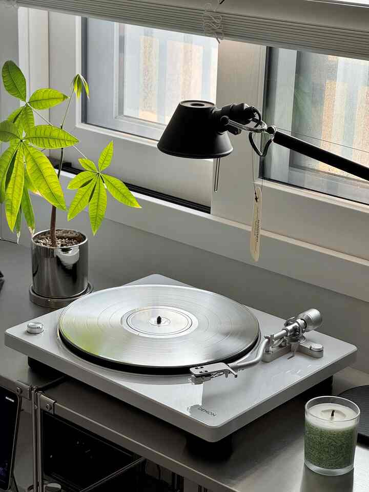 Ivory and gray toned small workspace featuring a Hi-Fi turntable and black desk lamp with natural decor