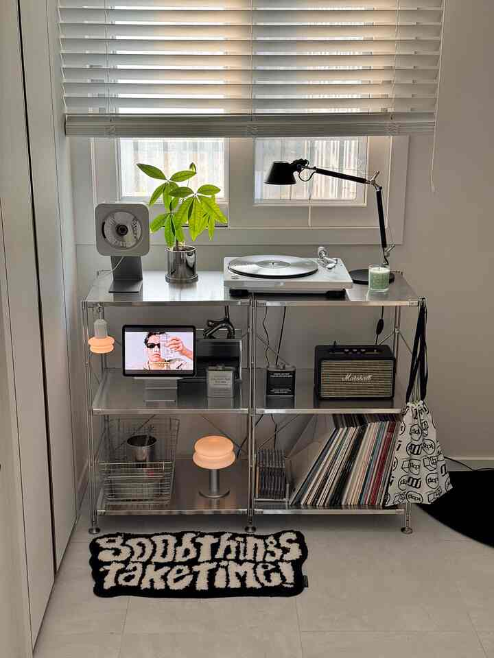 Silver stainless steel shelf in a modern living room music zone with turntable, LPs, lighting, and indoor plant
