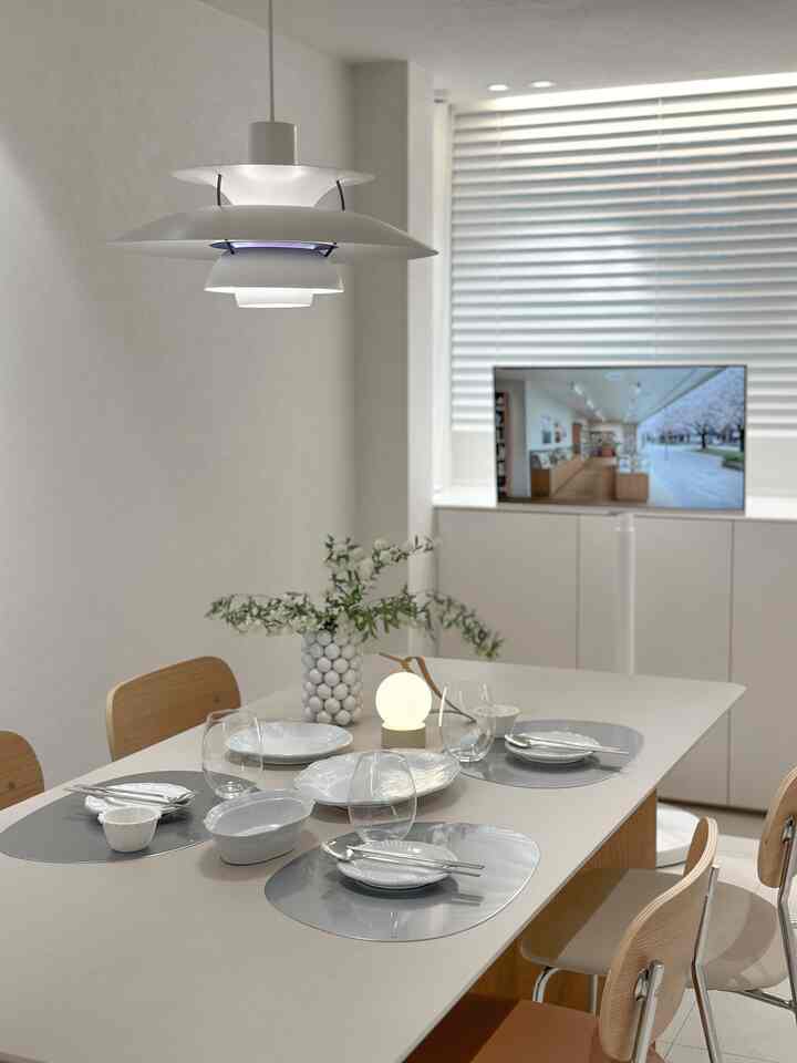 White and wood-toned dining room featuring a pendant light and dining set, creating a clean and modern atmosphere