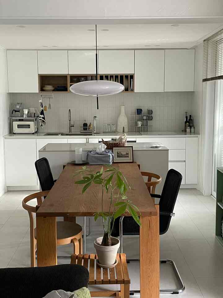 Modern dining room featuring white and wood tones, with a white oak dining table and assorted chairs creating a natural ambiance