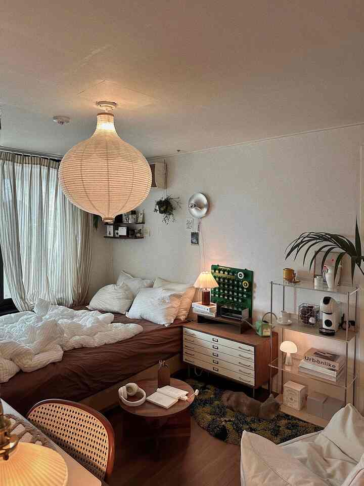 Wood tone and cream curtain bedroom featuring pendant light, bean bag, dresser with cozy natural light ambiance