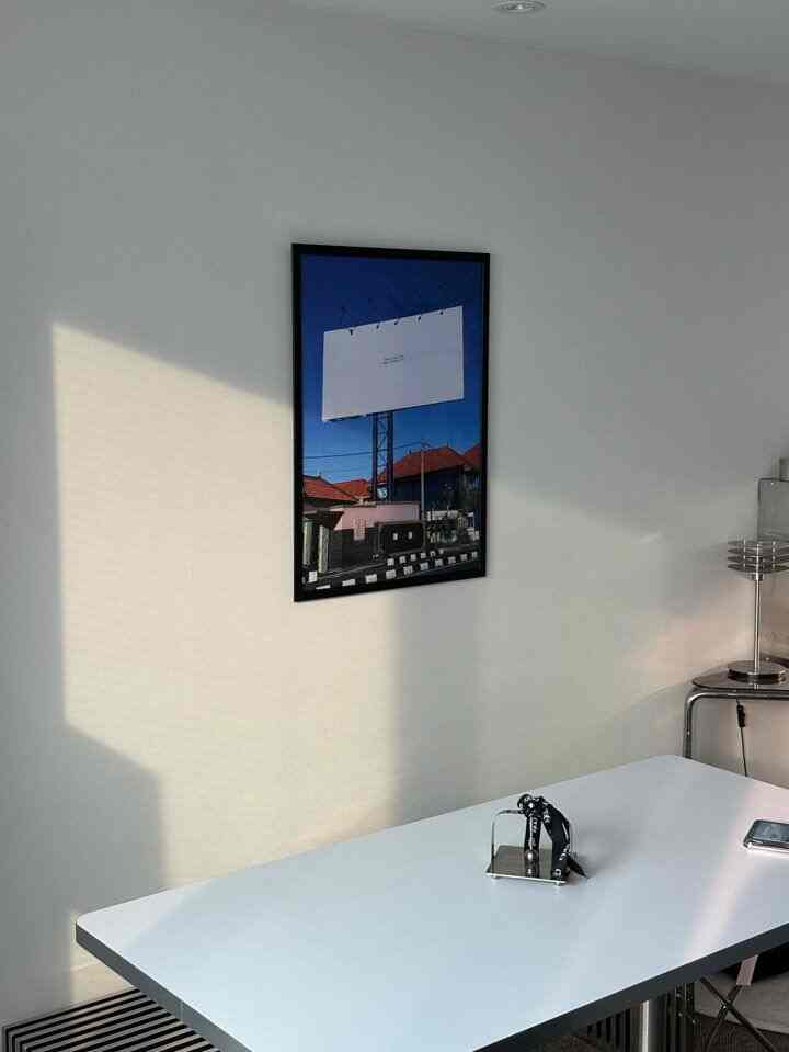 白を基調とした清潔感のある壁に額縁が飾られたミニマルな印象のインテリア