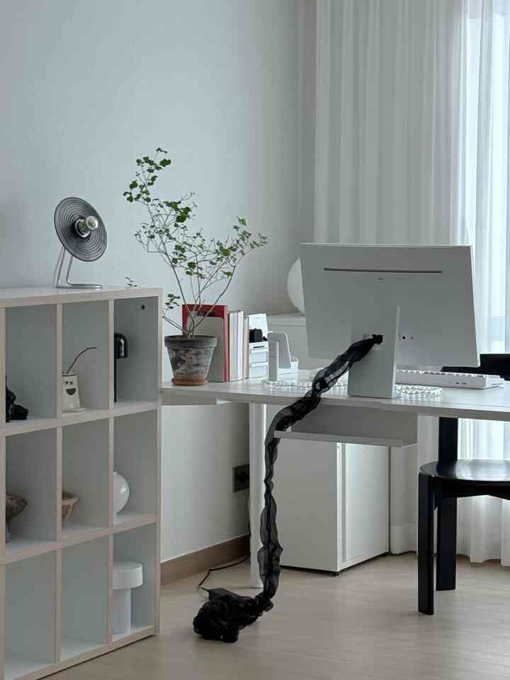 ホワイトとウッドトーンのリビングルームのホームオフィス、デスクとモニター、格子状の本棚が配置されたシンプルで清潔感のある空間