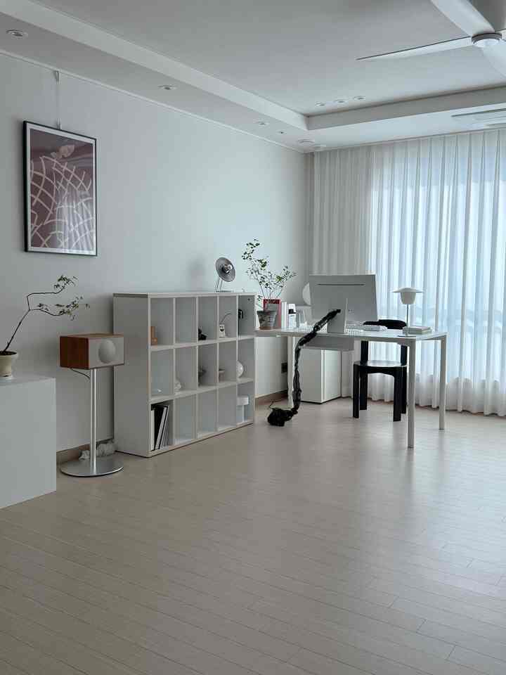 White and beige toned home office featuring clean desk and bookshelf in a minimalistic space