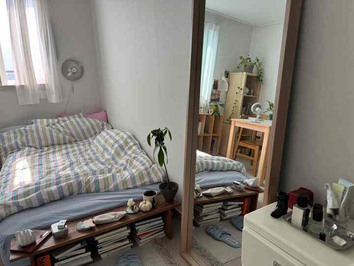 白と木目調が調和した小さな寝室、コンパクトなレイアウトとミニマルな家具構成が印象的な空間