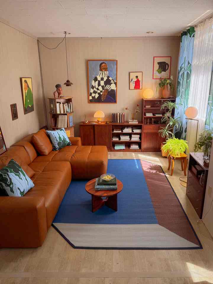 ナチュラルな色調のリビング、ブラウンレザーソファとブルーのパターンラグ、木製家具と植物が調和した温かみのあるインテリア