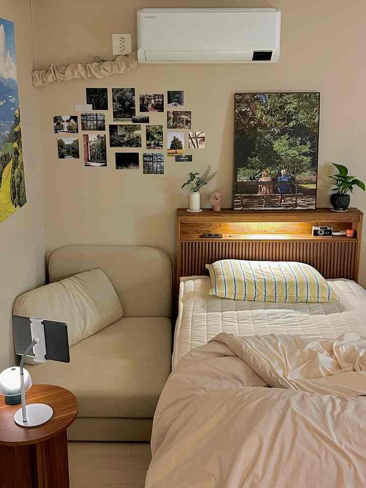 ベージュと木目調の色調のワンルーム寝室、ソファベッドとサイドテーブル、壁に飾られたインテリア額が落ち着いた雰囲気を作り出しています。