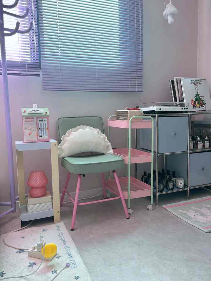 パステルカラーの小さなワンルーム、ピンクとミントの家具とブラインド、レコードプレーヤーが調和した雰囲気のあるカフェ風インテリア