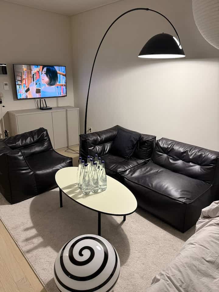 黒と白のトーンのリビング、レザーソファと円形テーブル、フロアランプが配置されたモダンな空間