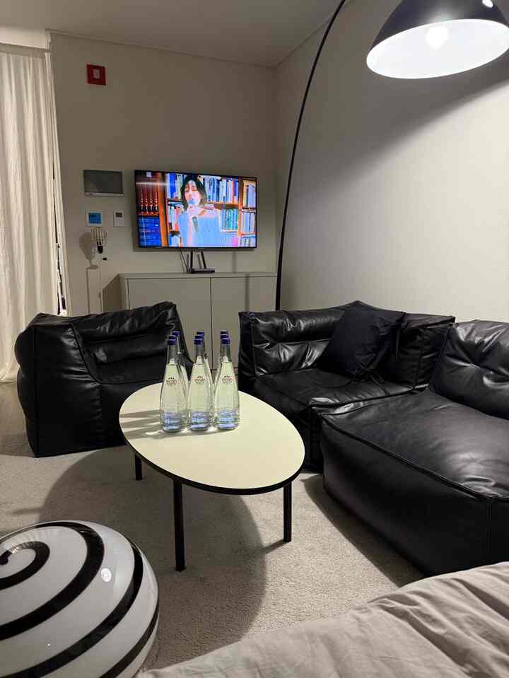 白と黒のトーンが調和したモダンなリビング、ブラックレザーソファとアーチ型フロアランプが配置された空間