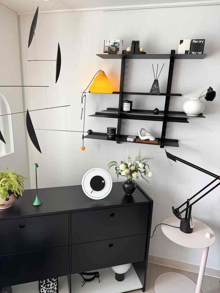 Modern black and white living room featuring wall shelves and storage cabinet with clean, minimalist decor