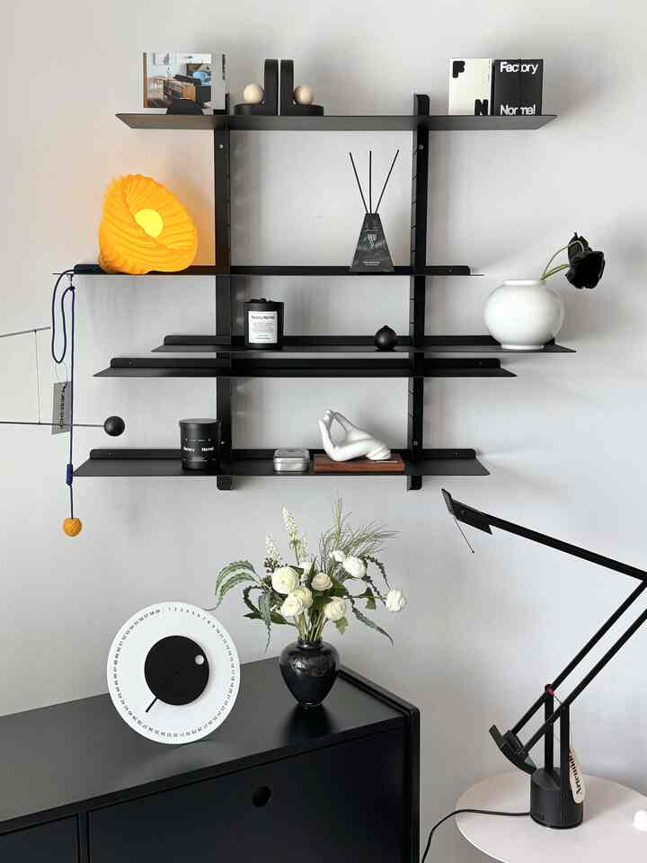 Modern and simple interior featuring white and black wall-mounted shelves with vases and clock