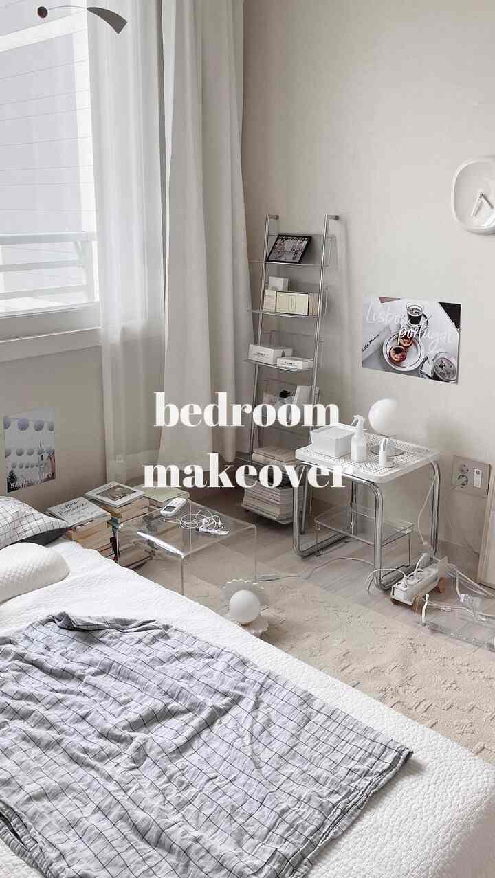 白とグレーの落ち着いた寝室、透明なテーブルとメタルシェルフが配置されたシンプルで清潔感のあるインテリア