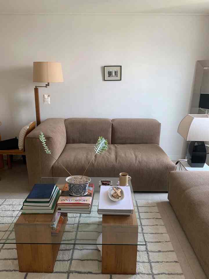 ナチュラルなベージュとブラウンの色調のリビング、中央にソファとガラスのコーヒーテーブルが配置されたモダンで落ち着いたインテリア