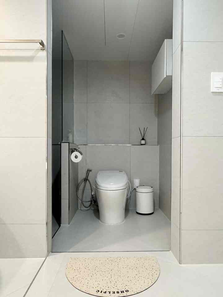 白とベージュの色調のバスルーム、モダンなトイレとオブジェのバスマットが配置された雰囲気のあるインテリア