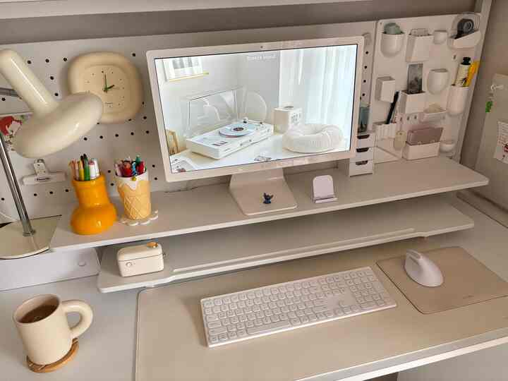 ホワイトとベージュのトーンでまとめられたホームオフィスのデスク、モニターと整理された収納アイテムが配置された清潔感のある在宅勤務空間