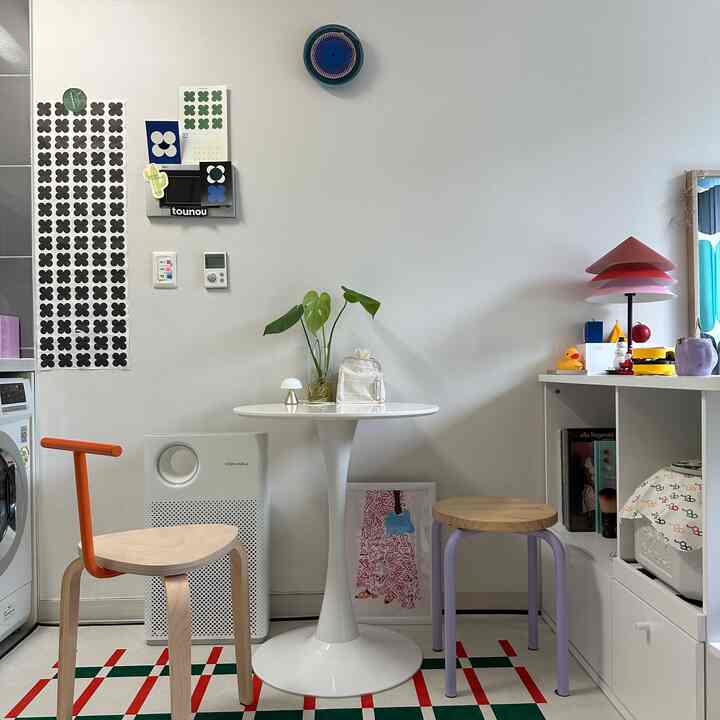 白と木目調が調和したコンパクトなカフェ風の一人暮らし空間、丸テーブルとスツールが配置されたインテリア