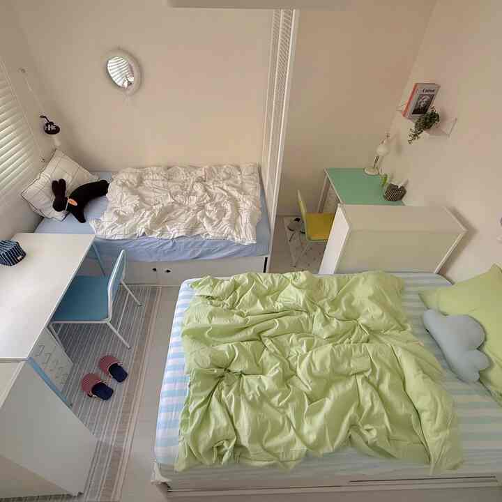 A clean and cozy kids' room in white and blue tones featuring two beds and desks
