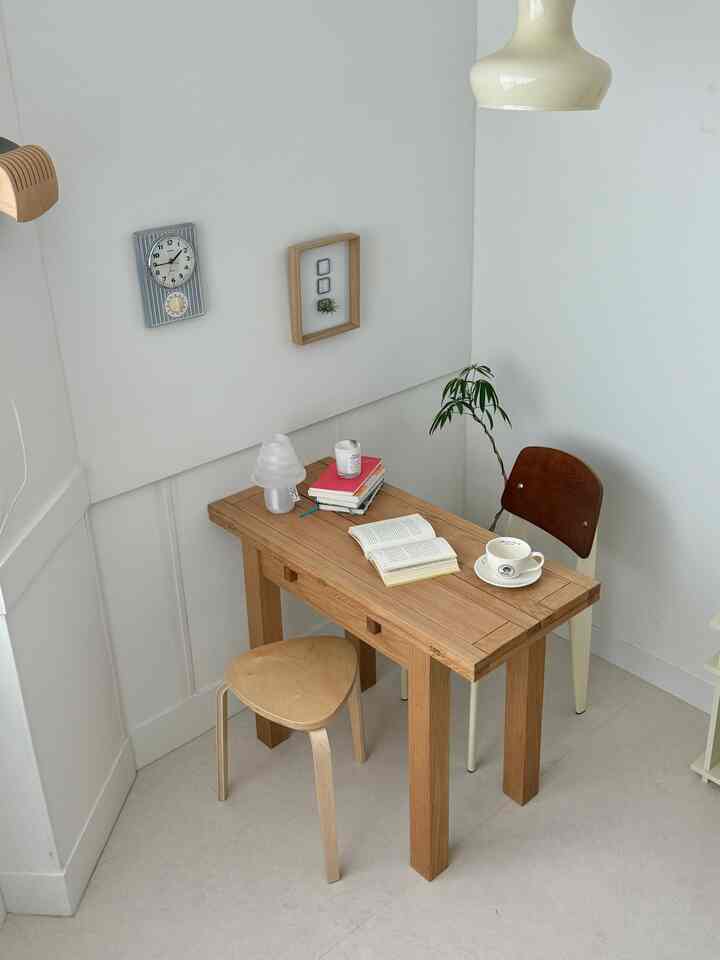 A small dining room with white walls and wood tone furniture, featuring books and coffee creating a cozy atmosphere